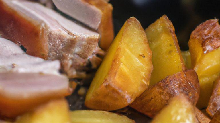 Imagem de costela de porco assada na airfryer com batatas assadas e ervas frescas. O prato é servido em um prato branco com uma fatia de limão ao lado.