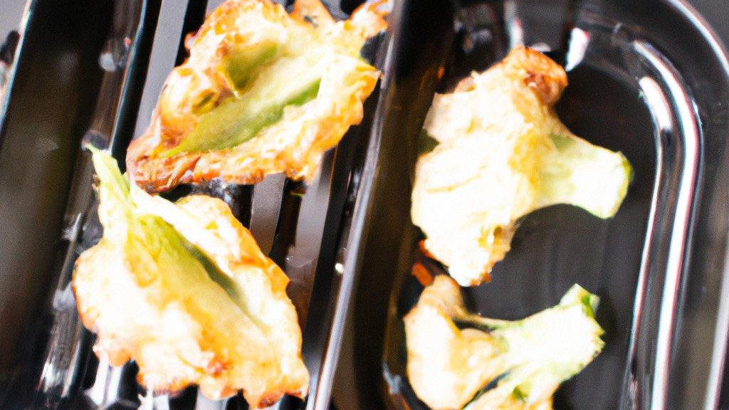 Imagem de uma couve-flor gratinada em uma Airfryer. A couve-flor é dourada e coberta com uma crosta de queijo borbulhante. A imagem é tomada de cima e o fundo da Airfryer é visível.
