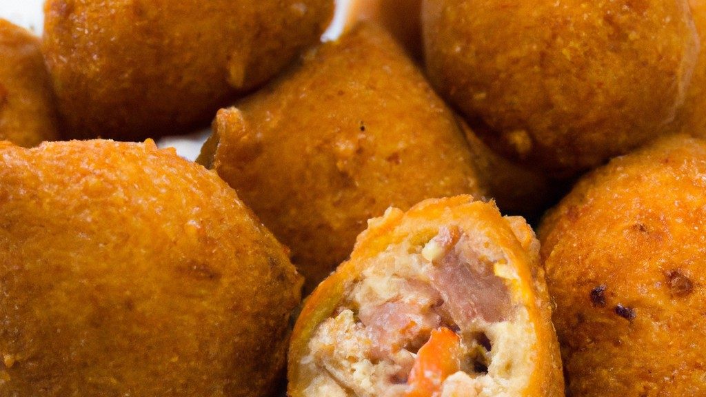 Imagem mostrando coxinhas de frango assadas em uma assadeira, sem pele e cobertas com uma crosta dourada e crocante. As coxinhas são servidas em uma travessa com um ramo de alecrim fresco.