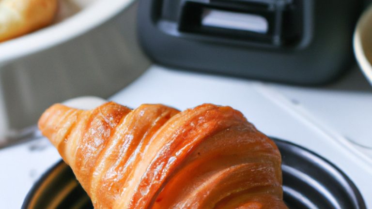 Imagem de um croissant dourado e escamoso cozido em uma Airfryer Lidl. O croissant é colocado em um prato branco e tem um interior macio e amanteigado.