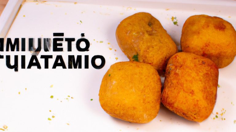 Imagem mostra um prato de croquetes de mandioca dourados e crocantes, dispostos em cima de uma superfície branca. Os croquetes têm uma forma oval e são polvilhados com ervas secas. Ao fundo, há uma airfryer com sua porta aberta.