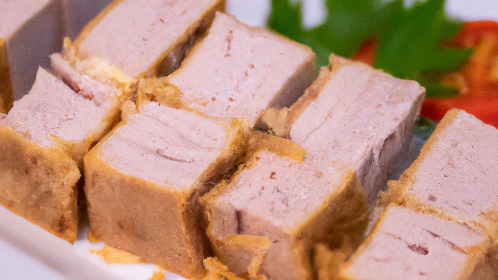 Imagem de cubos de atum empanados e dourados cozidos em uma airfryer. Os cubos são servidos em um prato com um molho para acompanhamento.