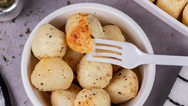 Imagem de dadinhos de tapioca dourados e crocantes preparados na airfryer, servidos em um prato com calda de frutas vermelhas ao lado.