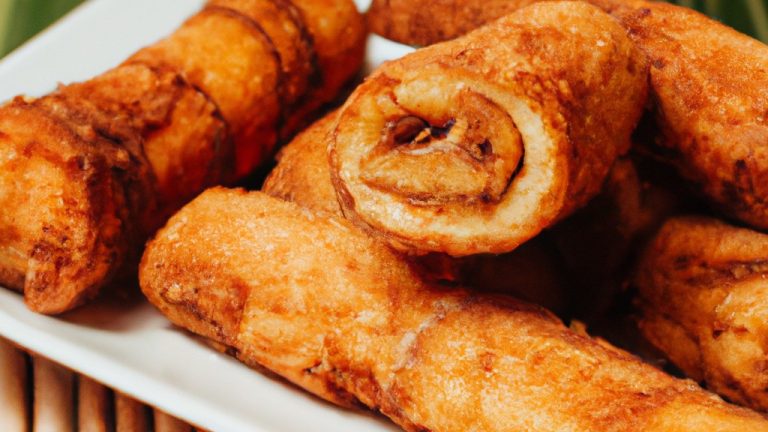 Imagem de enroladinhos de banana fritos na airfryer, polvilhados com canela. Esses enroladinhos são uma guloseima deliciosa e fácil de preparar.