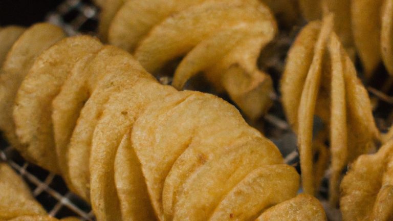 Imagem de espirais de batata douradas e crocantes preparadas em uma Airfryer. As espirais são dispostas em formato de círculo, sobrepostas umas às outras, criando um visual texturizado e apetitoso.
