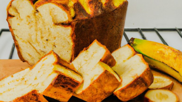 Uma fotografia de um pão de banana caseiro cozido em uma airfryer. O pão é marrom dourado e tem uma crosta crocante. É coberto com nozes e bananas fatiadas.