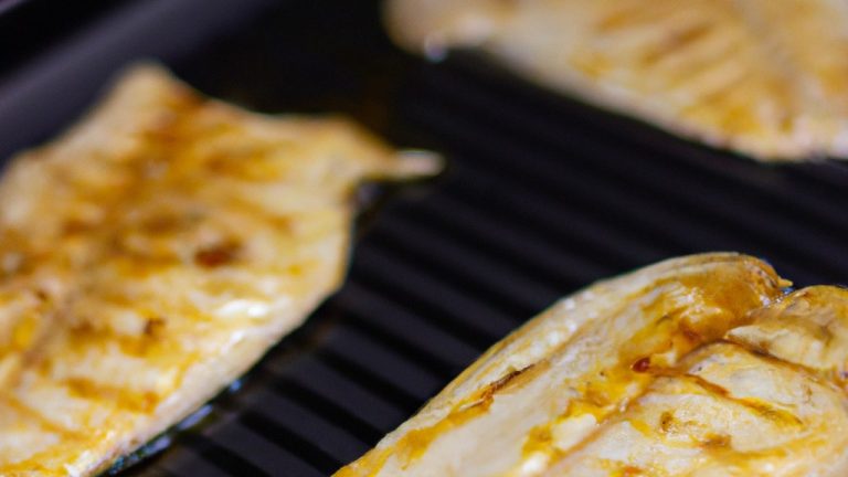 Filé de tilápia cozido no forno ou fritadeira, com pele dourada e crocante. O peixe é temperado com ervas e especiarias, e servido com fatias de limão e ervas frescas.