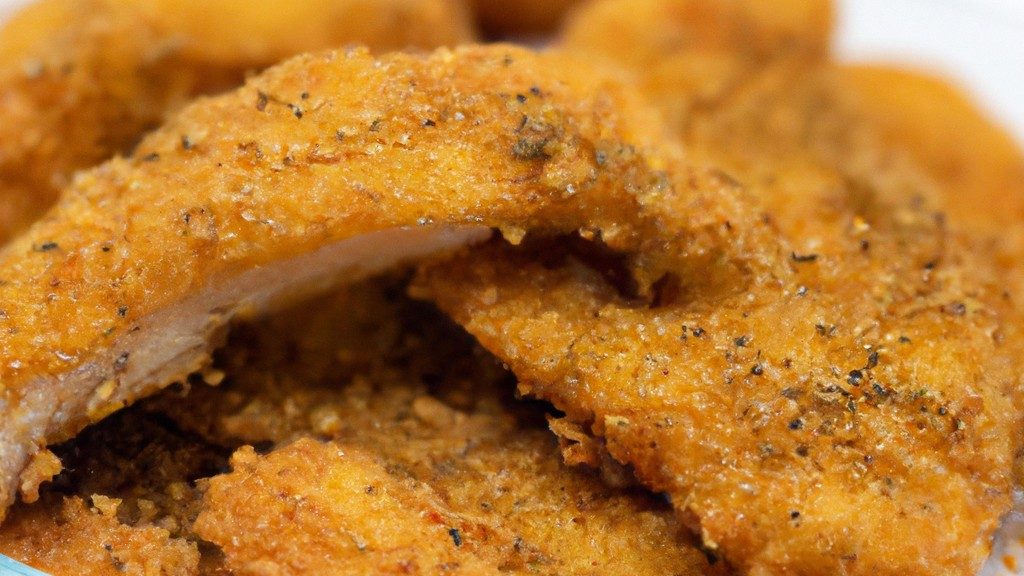 Imagem de um filé de dourada crocante e dourado cozido em uma Airfryer. O peixe é servido em um prato com rodelas de limão e ervas frescas.
