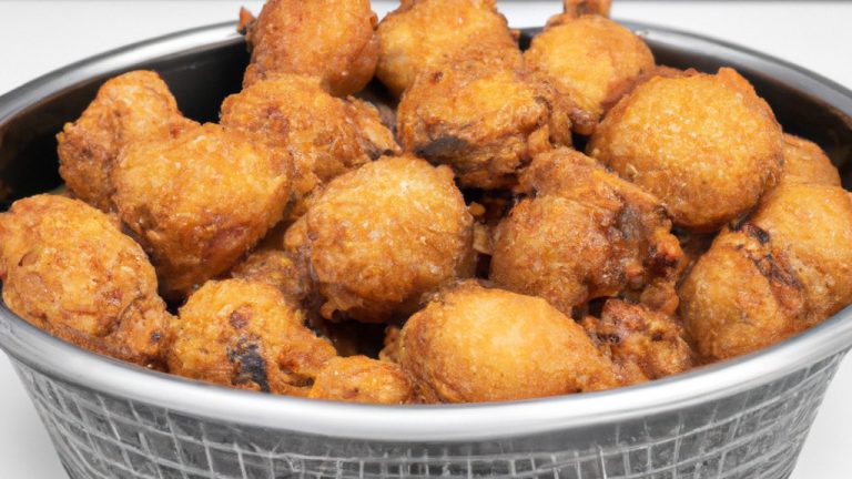 Foto de filetes de peixe empanados crocantes cozidos em uma fritadeira. Os filetes são dourados e têm uma crosta escamosa. Eles são servidos em um prato com fatias de limão e um molho tártaro.