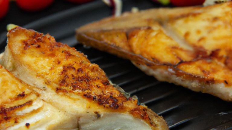 Imagem de iscas de peixe empanadas e douradas com legumes coloridos como brócolis, cenoura e pimentão, tudo cozido em uma airfryer.