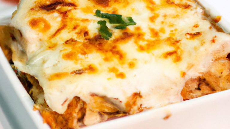 Imagem de uma lasanha de frango cremosa feita na Airfryer. A lasanha é feita com camadas de massa de lasanha, frango cozido, molho cremoso, queijo e espinafre. A lasanha é assada até dourar e borbulhar.