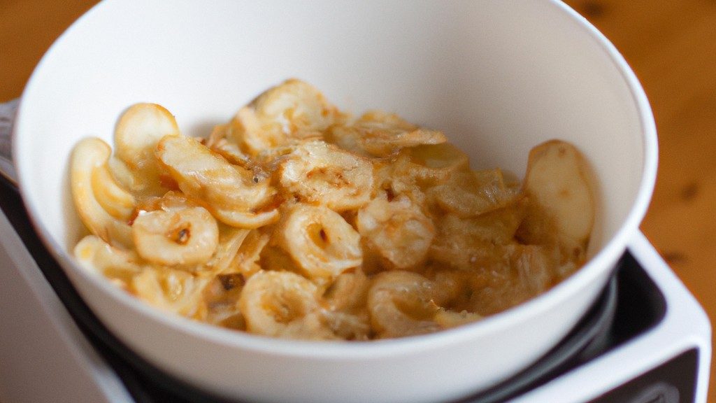 Imagem mostra um prato de macarrão cremoso cozido em uma Airfryer, ao lado de ingredientes como leite, creme de leite, queijo parmesão e macarrão.