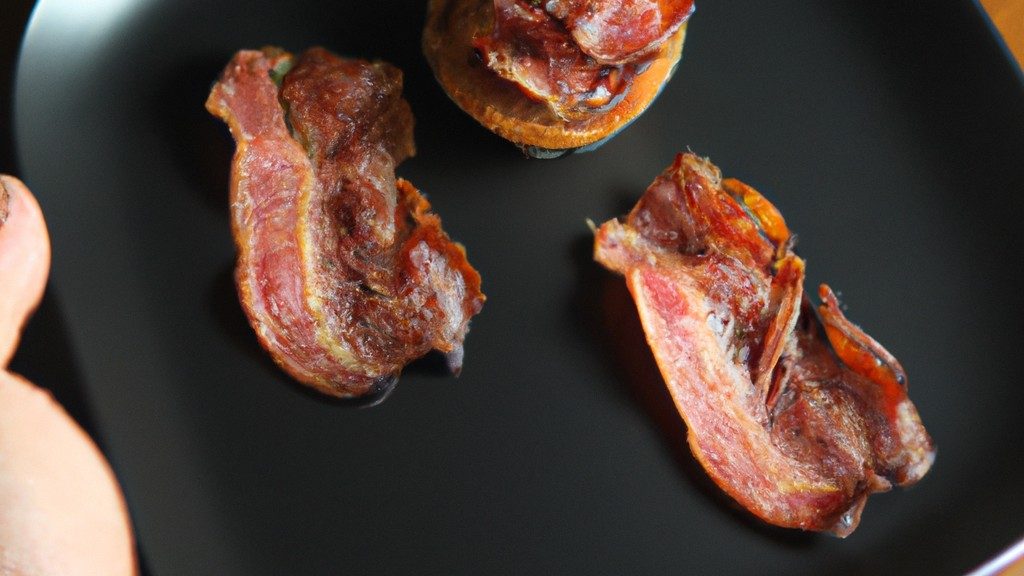 Foto de um medalhão de filé mignon envolto em bacon, cozido em uma Airfryer. O medalhão é dourado e crocante por fora e suculento e rosado por dentro. Ele é guarnecido com alecrim fresco e servido com um molho de sua preferência.