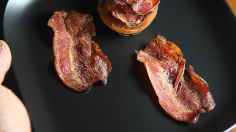 Foto de um medalhão de filé mignon envolto em bacon, cozido em uma Airfryer. O medalhão é dourado e crocante por fora e suculento e rosado por dentro. Ele é guarnecido com alecrim fresco e servido com um molho de sua preferência.