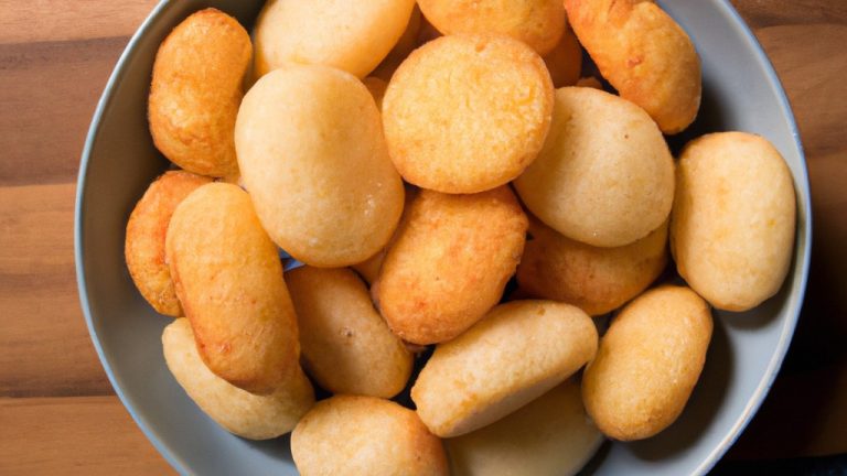 Imagem de um medalhão de mandioca com queijo assado em uma Airfryer. O medalhão é dourado e crocante, com queijo derretido e borbulhante no topo. A mandioca é macia e fofa por dentro.