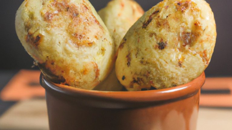 Imagem de um medalhão de mandioca frito no ar, em uma fritadeira. O medalhão é dourado e crocante, e está servido em um prato com um molho de tomate ao lado.