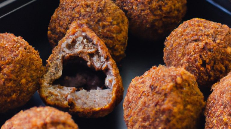 Imagem de mini quibes recheados dourados e crocantes fritos na airfryer, apresentados em um prato com rodelas de limão. A receita oferece instruções passo a passo para preparar esses quitutes saborosos e práticos.