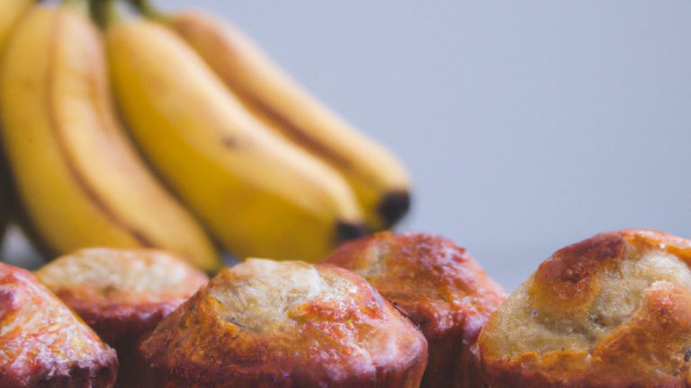 Imagem de muffins de banana recém-assados na airfryer, com gotas de chocolate por cima. Os muffins são dourados e fofos, e o fundo da assadeira é forrado com papel manteiga.