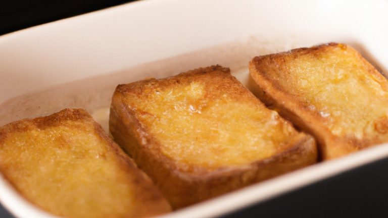 Imagem de torradas francesas douradas e crocantes em uma Airfryer, polvilhadas com açúcar em pó e servidas com calda de bordo.