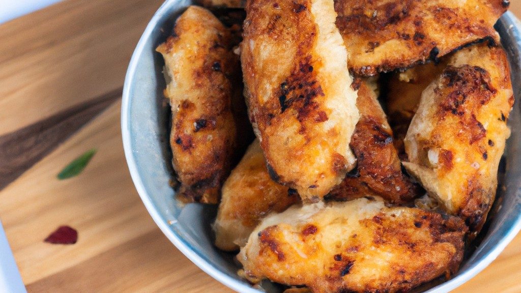 Imagem de Nuggets de Atum na Airfryer prontos, empanados e dourados em um prato branco com um ramekin de molho ao lado.