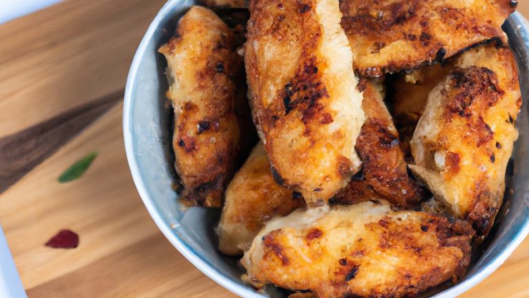 Imagem de Nuggets de Atum na Airfryer prontos, empanados e dourados em um prato branco com um ramekin de molho ao lado.