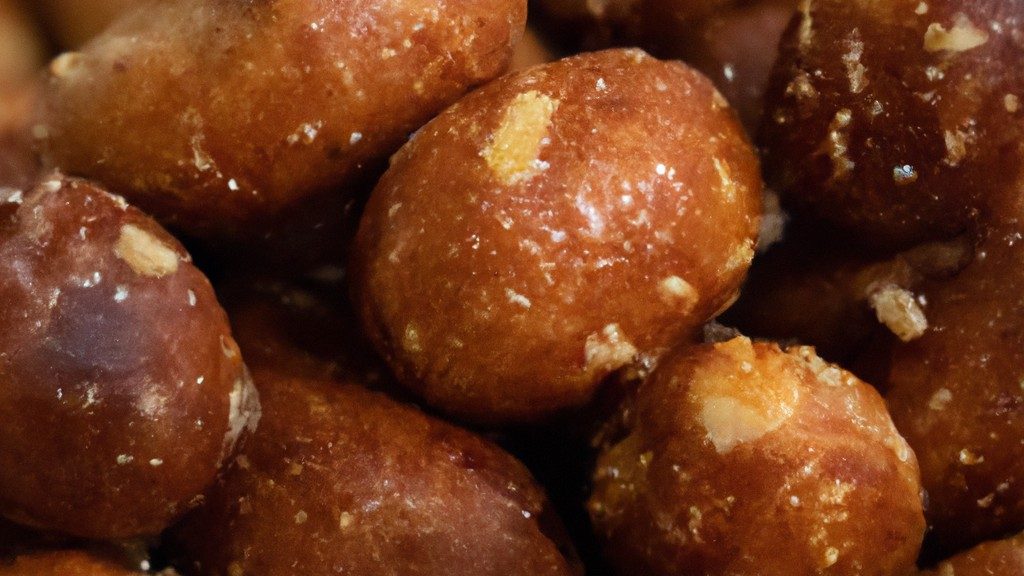 Imagem de nozes caramelizadas em uma tigela, com um fundo de tábuas de madeira. As nozes são cobertas com uma camada crocante e caramelada, com um brilho dourado.