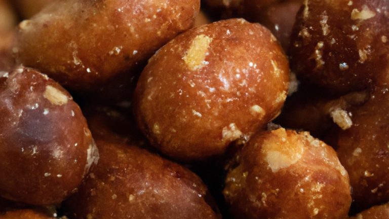 Imagem de nozes caramelizadas em uma tigela, com um fundo de tábuas de madeira. As nozes são cobertas com uma camada crocante e caramelada, com um brilho dourado.