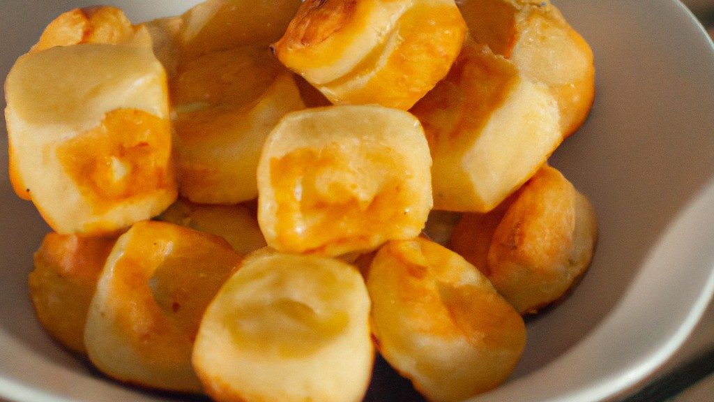 Foto de palitinhos de pão dourados e crocantes fritos em uma Airfryer, acompanhados de um pote de molho para imersão.