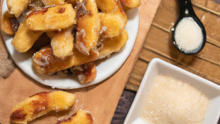 Imagem de palitinhos de banana crocantes e dourados em uma frigideira, polvilhados com queijo parmesão ralado. Os palitinhos são finos e cortados na diagonal, criando uma apresentação atraente.