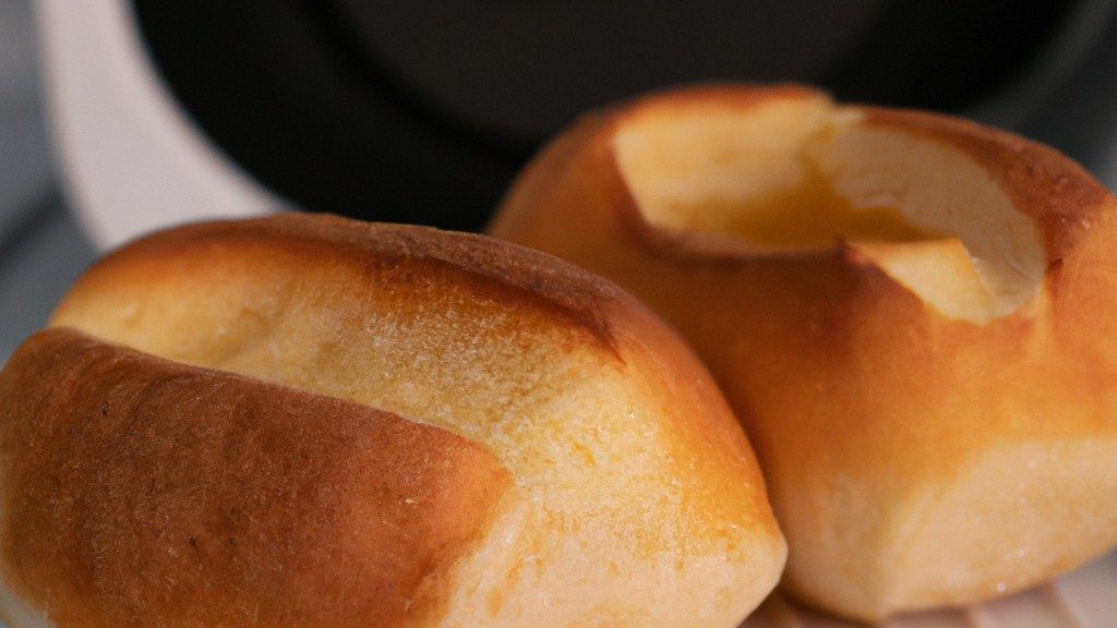 Imagem de pão de forma com queijo derretido, feito na Airfryer. A foto mostra o pão cortado em quatro triângulos, com o queijo derretido por cima. A Airfryer está aberta ao fundo, e a bandeja de cozimento é visível.
