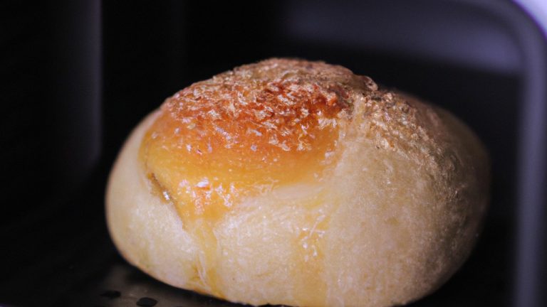 Pão de leite caseiro, preparado na airfryer, com baixo teor de carboidratos e fácil de fazer. A imagem mostra um pão dourado e crocante com uma crosta marrom clara, colocado em uma superfície de madeira. A receita é uma ótima opção para aqueles que desejam desfrutar de pão fresco e saboroso sem comprometer sua dieta low carb.