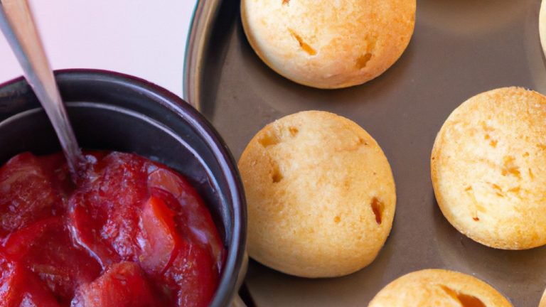Imagem mostrando pão de queijo recheado com goiabada, cozido na airfryer. Os pães de queijo estão dourados e crocantes, com o recheio de goiabada derretido e pegajoso. A imagem transmite uma sensação de calor e conforto, e o pão de queijo parece delicioso.
