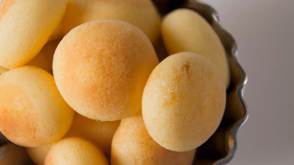 Imagem de pães de queijo de batata-doce recém-assados em uma cesta de fritadeira. Os pães de queijo são dourados e crocantes, com uma textura macia por dentro.
