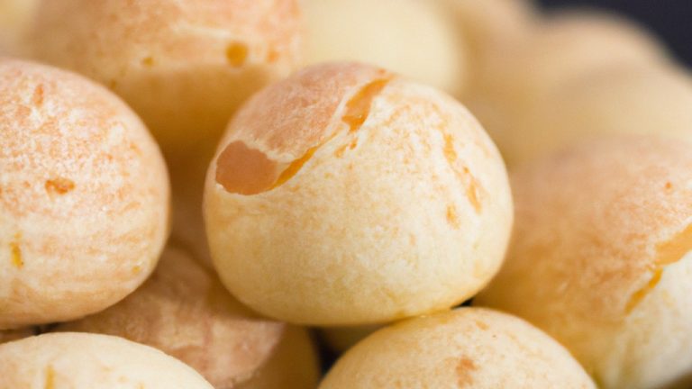 Imagem de pães de queijo dourados e crocantes feitos no liquidificador e cozidos na air fryer. Eles estão dispostos em um prato branco e têm uma textura crocante e um interior macio e arejado.