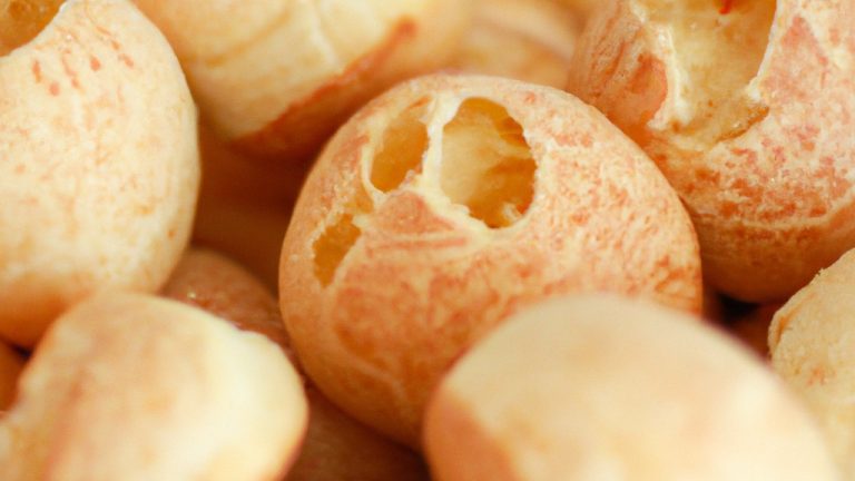 Imagem mostra uma cesta de air fryer contendo vários pães de queijo dourados e crocantes. Esses pães de queijo são uma opção leve e saborosa, feita com ingredientes saudáveis e sem glúten.