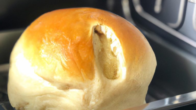 Uma foto de um pão francês crocante e dourado dividido ao meio, com um recheio generoso de requeijão cremoso e derretido. O pão é assado em uma Airfryer, o que lhe confere uma textura exterior crocante e um interior macio e fofo.