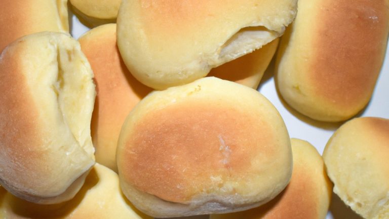 Imagem de pães italianos recém-assados em uma cesta, com uma tigela de azeite ao lado. Os pães são dourados e crocantes, com uma crosta crocante e um miolo macio e arejado. O azeite é claro e dourado, com um aroma fresco e frutado.