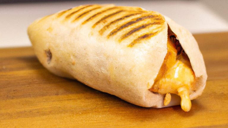 Imagem de um pão pita aberto ao meio e recheado com fatias de frango grelhado, tomate picado, cebola roxa picada, alface picada e molho de iogurte. O pão pita está assado numa Airfryer e tem um aspecto dourado e crocante.