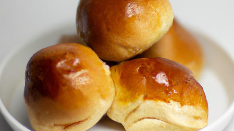 Imagem de pães doces dourados e fofos em uma cesta. Os pães são polvilhados com açúcar e têm uma aparência caseira e apetitosa.