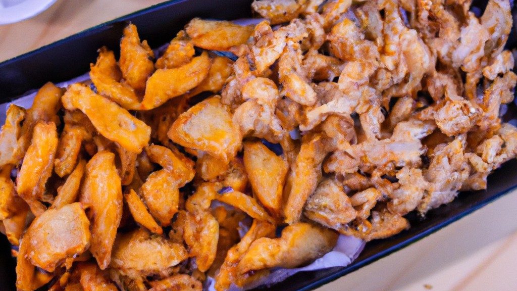 Imagem de filé de peixe empanado e assado ao lado de batatas fritas de mandioca em um prato branco.