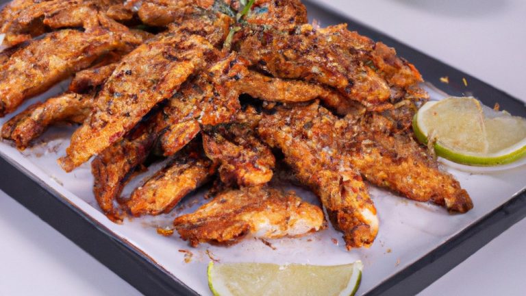 Imagem de um peixe frito e dourado em uma airfryer, com um molho vermelho derramado por cima. O peixe está em um prato branco, cercado por fatias de limão e ervas frescas.