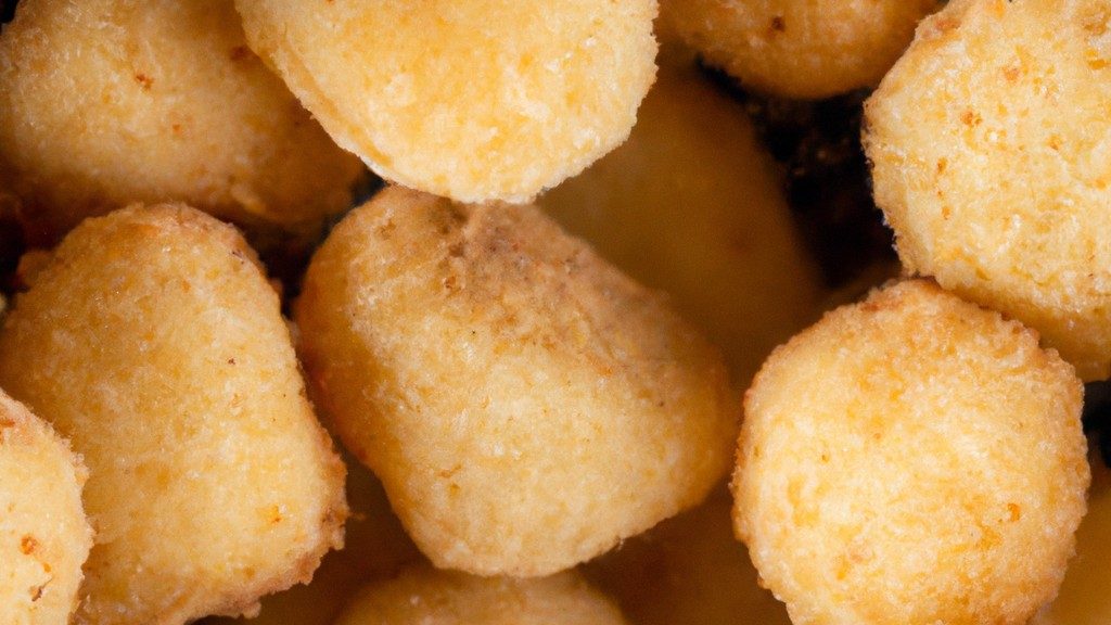 Imagem de grão de bico crocante e dourado espalhado em uma tigela. Os grãos são temperados com especiarias e ervas, e são uma opção de petisco saudável e saborosa.