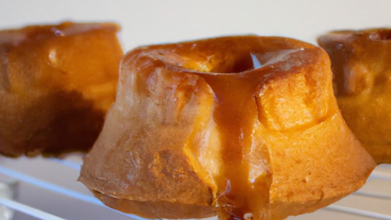 Imagem de um petit gâteau de doce de leite cozido na Airfryer. O bolinho está em uma forma de silicone e tem uma crosta dourada crocante. O doce de leite está borbulhando e derretendo no centro do bolinho. A imagem é tirada de cima e o fundo é branco.