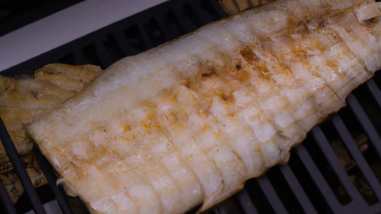 Imagem de uma posta de bacalhau assada na Airfryer. O peixe está dourado e crocante por fora, e branco e escamoso por dentro. É servido com um limão cortado ao lado.