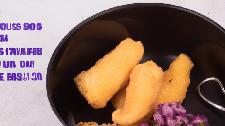 **Texto alternativo:**
Uma cesta da Airfryer contém postas de bacalhau cozidas e douradas, guarnecidas com limão e ervas frescas.