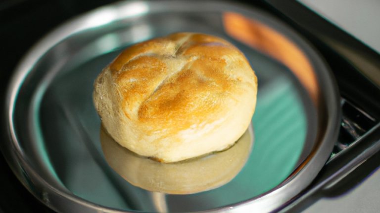 Imagem de uma assadeira cheia de fatias de pudim de pão assadas até dourar em uma Airfryer. A assadeira está colocada sobre uma superfície de madeira e há uma espátula de metal próxima.