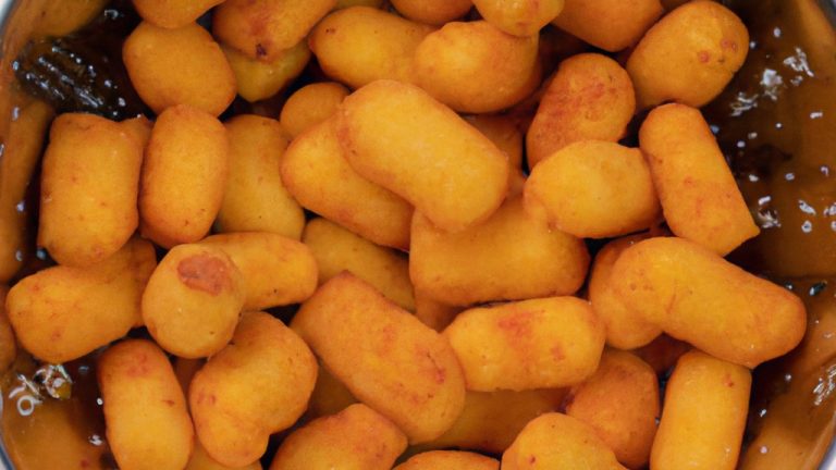 Imagem de queijo coalho frito na Airfryer. O queijo é dourado e crocante por fora, e macio e derretido por dentro. Ele está cortado em pedaços e servido com um molho de tomate.