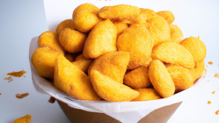 Imagem de queijo empanado frito até dourar em uma airfryer. O queijo é coberto com farinha, ovo e farinha de rosca antes de ser frito. O queijo é servido com um molho de tomate.