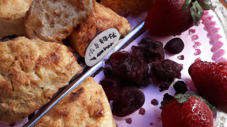 Imagem de scones de framboesa recém-assados em uma Airfryer, com uma tigela de framboesas frescas ao lado. Os scones são dourados e escamosos, com framboesas vermelhas brilhantes embutidas na massa.