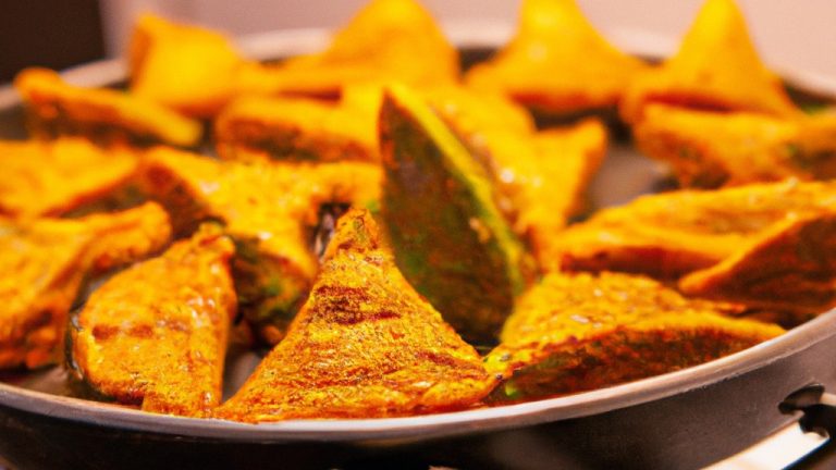 Imagem de quibe de abóbora empanado na airfryer, cortado em pedaços e disposto em um prato. A abóbora é laranja brilhante e o empanado é dourado e crocante. Ao fundo, há um recipiente de molho tahine.
